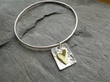 Sterling silver bangle with brass heart tag.