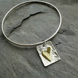 Sterling silver bangle with brass heart tag.